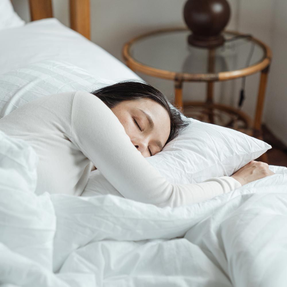 frau schlaeft im bett bettwaesche