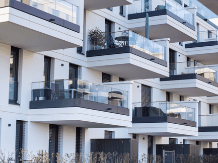 Fassade eines modernen Mehrfamilienhauses mit mehreren Balkonen und Glasgeländern.