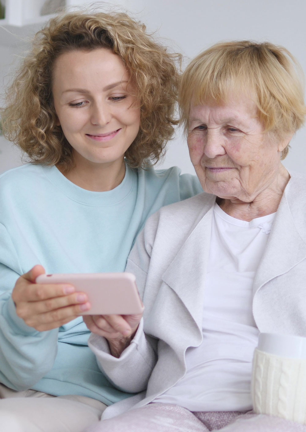 Senior mother and daughter looking at mobile