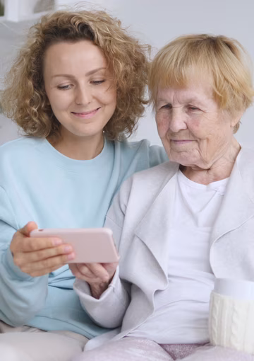 Senior mother and daughter looking at mobile