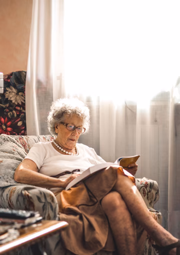 Senior woman sitting in chair reading a book