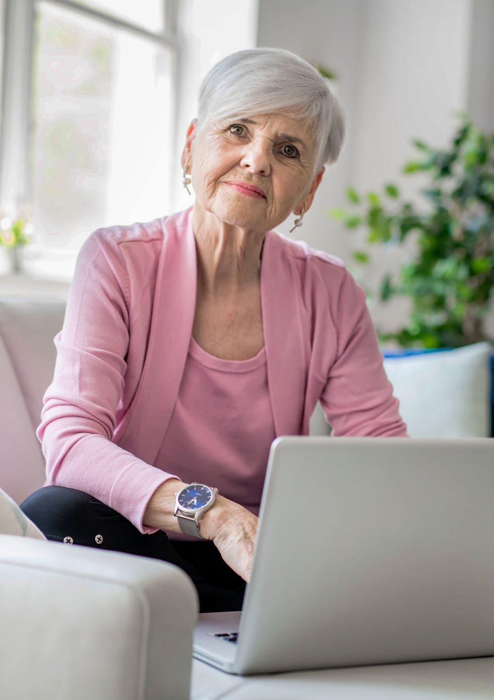 Retired senior woman sitting at home using her laptop