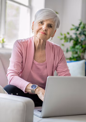 Retired senior woman sitting at home using her laptop