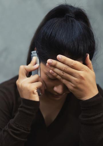 Woman with on the phone with her head in her hands