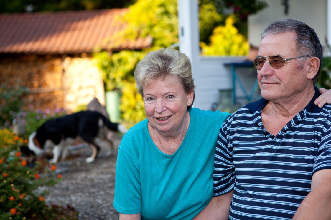 Senior couple sitting in front of their house.