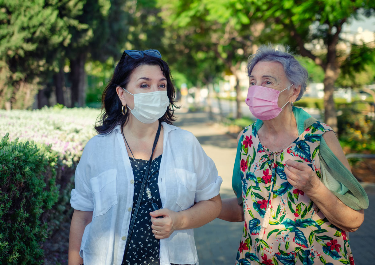Senior woman and carer going for a walk, wearing covid masks