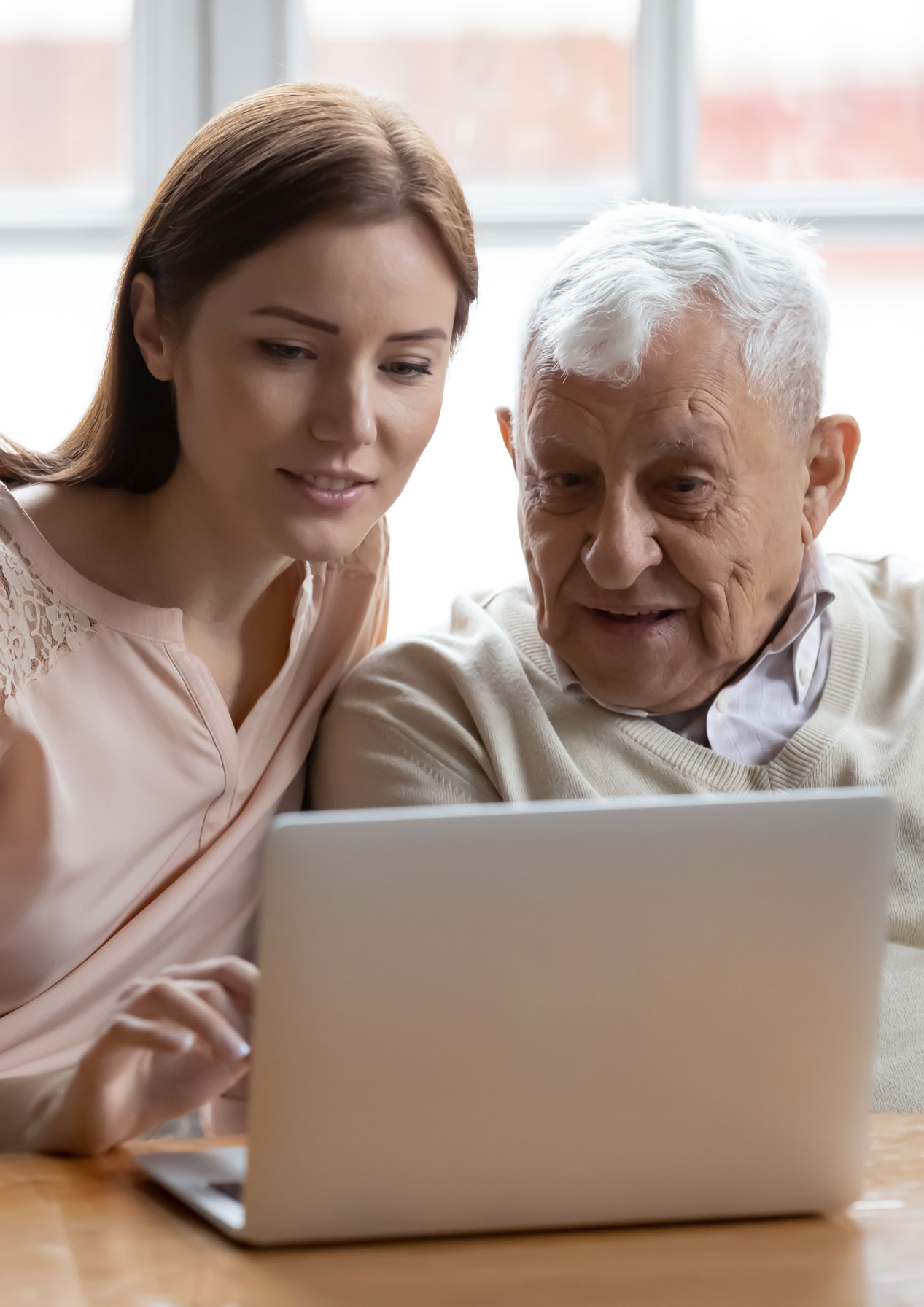 Senior man and adult daughter looking at laptop screen