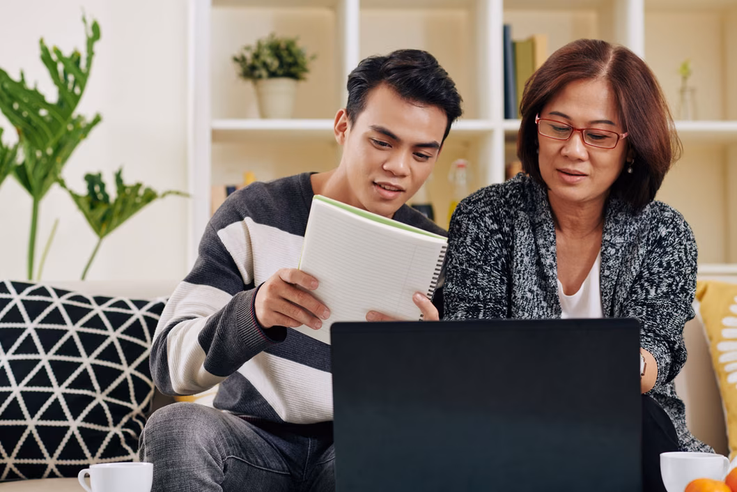Adult son helps his mother on laptop