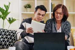 Adult son helps his mother on laptop