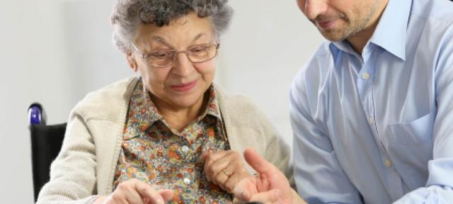 Image on an older woman wearing glasses reviewing paperwork with a young man