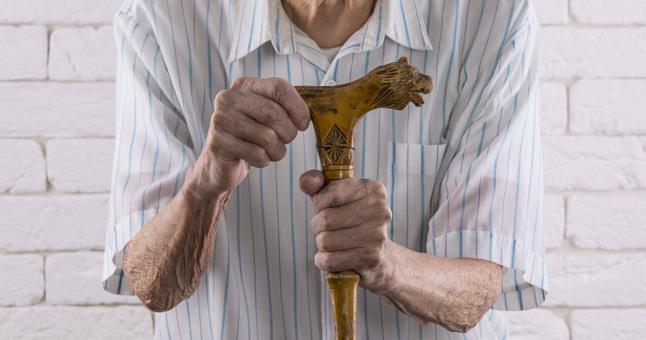 Senior mans hands holding a walking cane