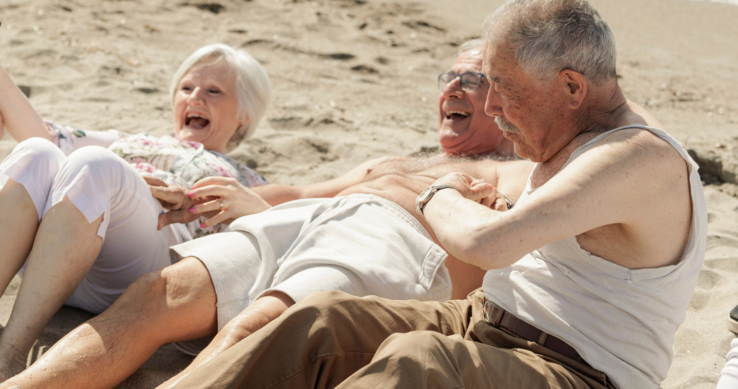 Older people at the beach laughing and enjoying themselves