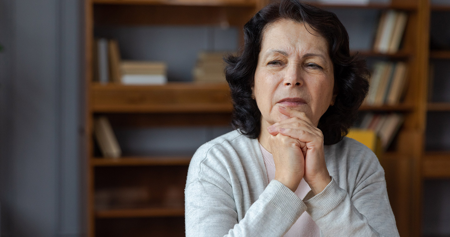 Image of an older woman resting her chin on folded hands