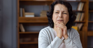 Image of an older woman resting her chin on folded hands