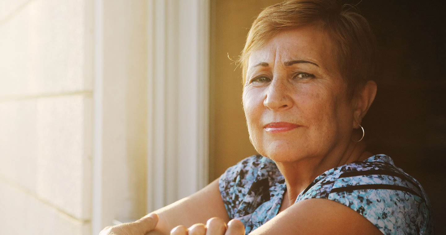 Older woman leaning out of window looking to camera