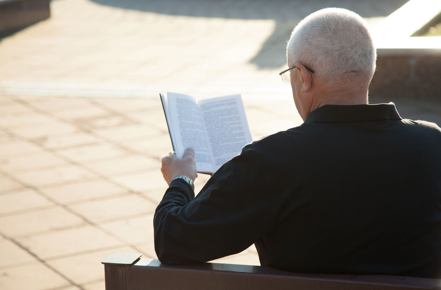 Senior man sitting on a bench reading