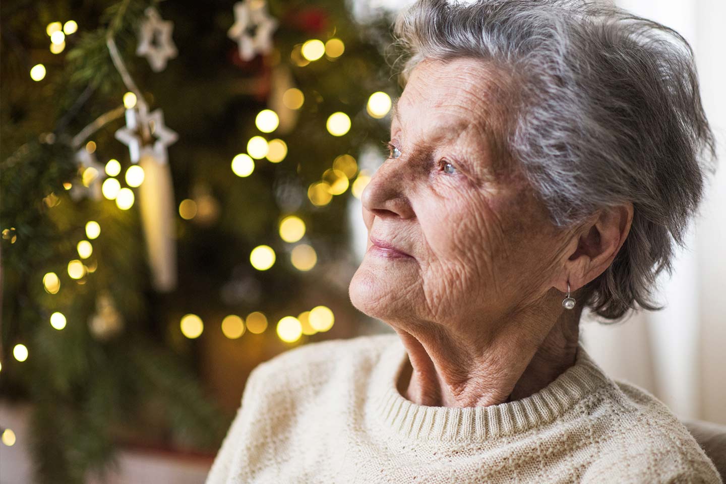 Photo of a woman in a cream knit in front of a christmas tree