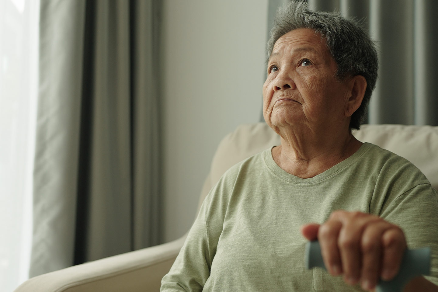 Photo of woman in a sage green top holding a walking stick