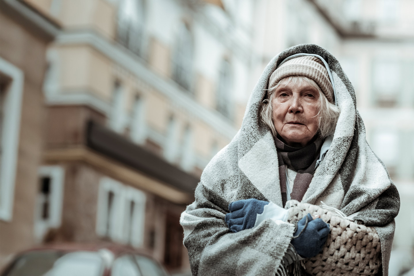 Photo of an older woman wrapped in blankets and woollens