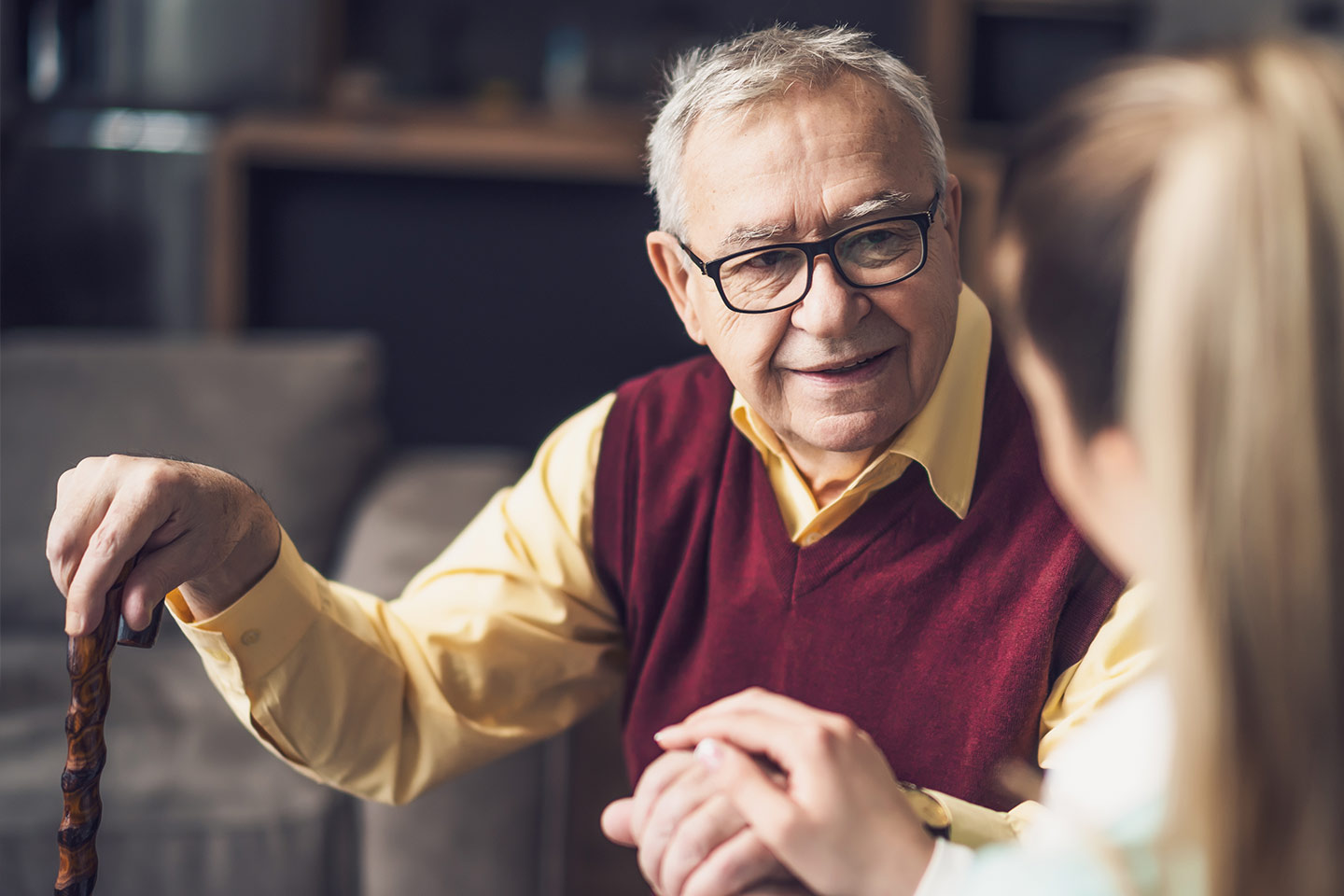 Photo of a man in a maroon vest with a walking cane