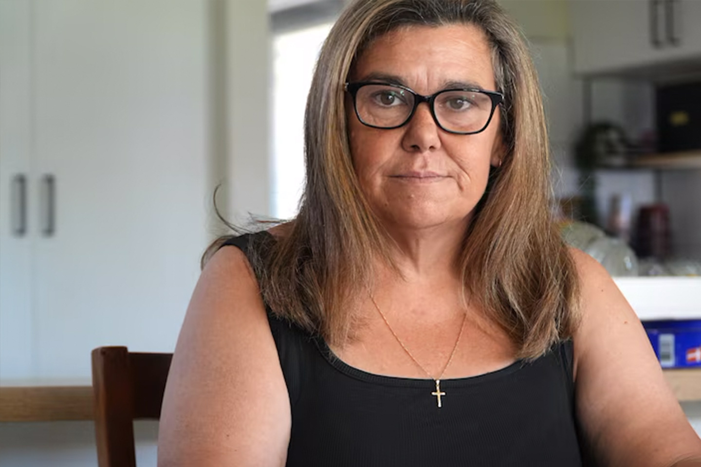 Photo of woman in black top and glasses wearing a crucifix