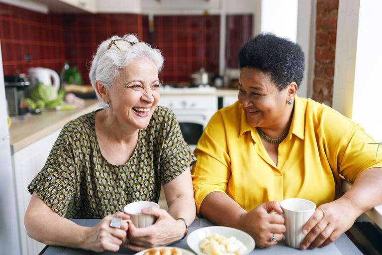 Image of two women having a coffee together and laughing.