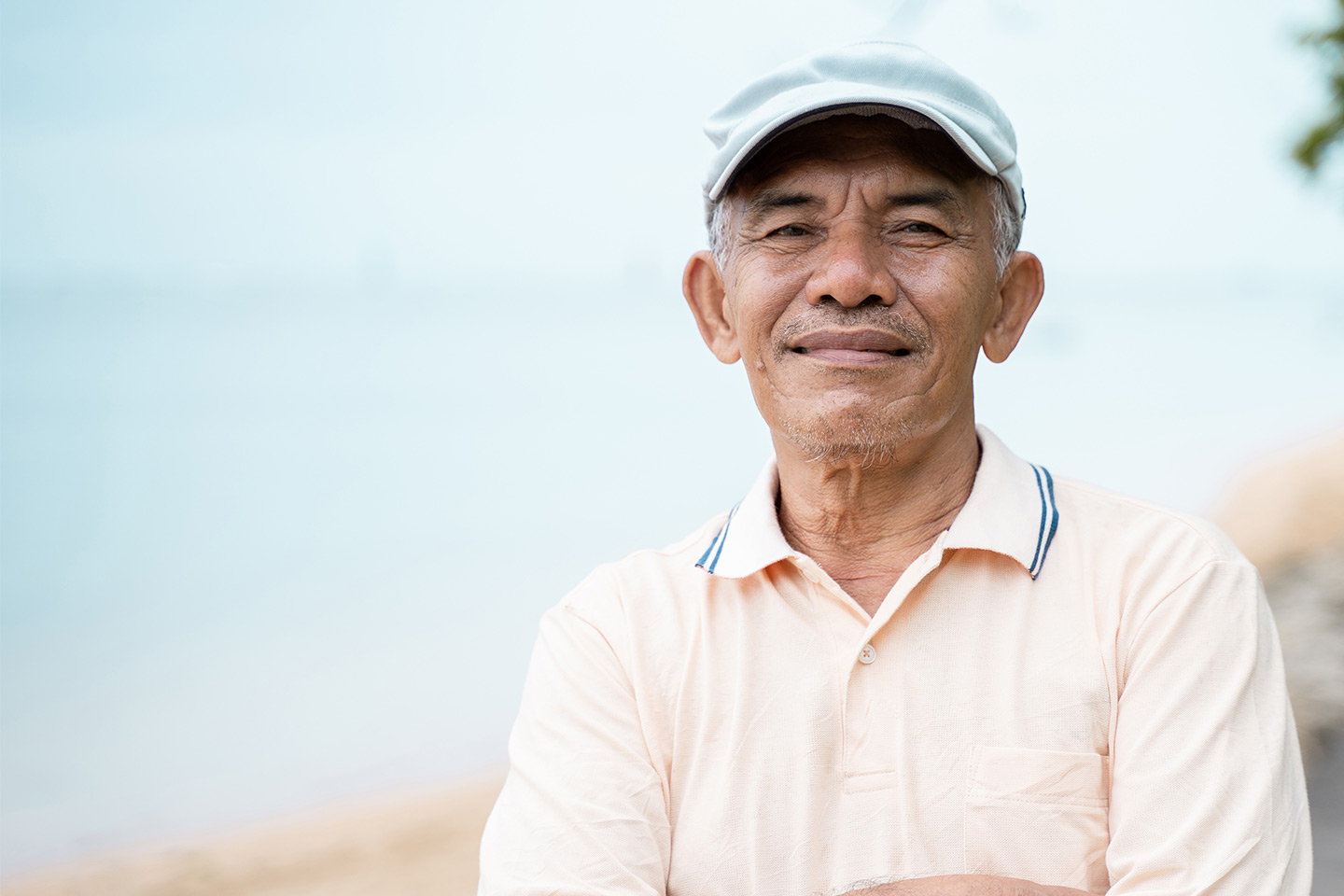 Photo of a man in a pale salmon polo and baby blue cap