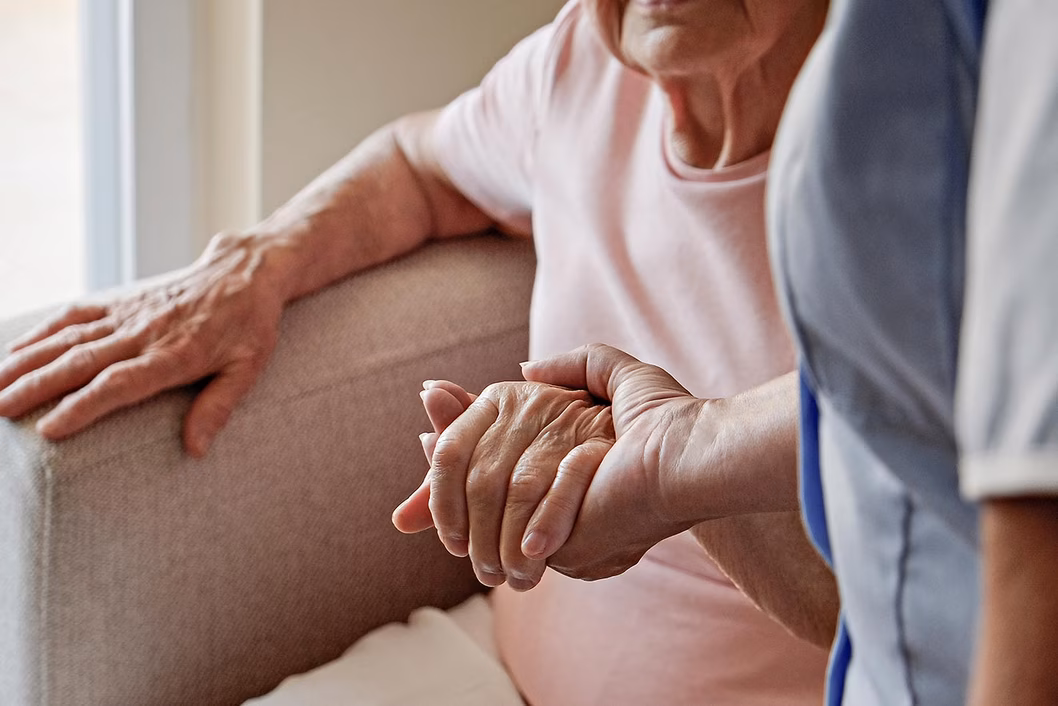 Photo of a nurse holding a seated woman's hand