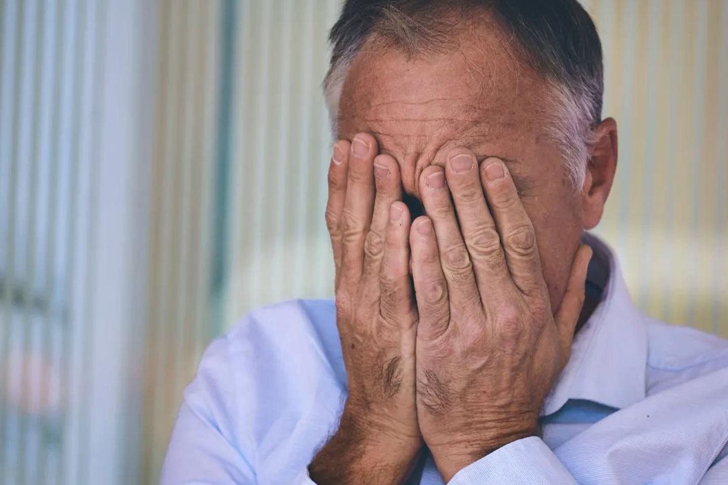 Photo of man with both his hands over his face