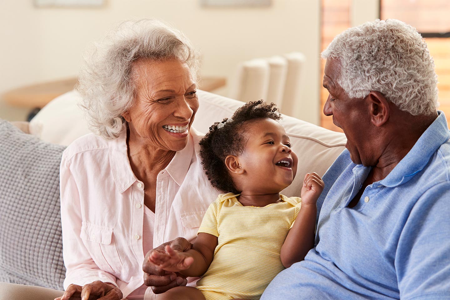 Photo of a laughing toddler sitting between two older people