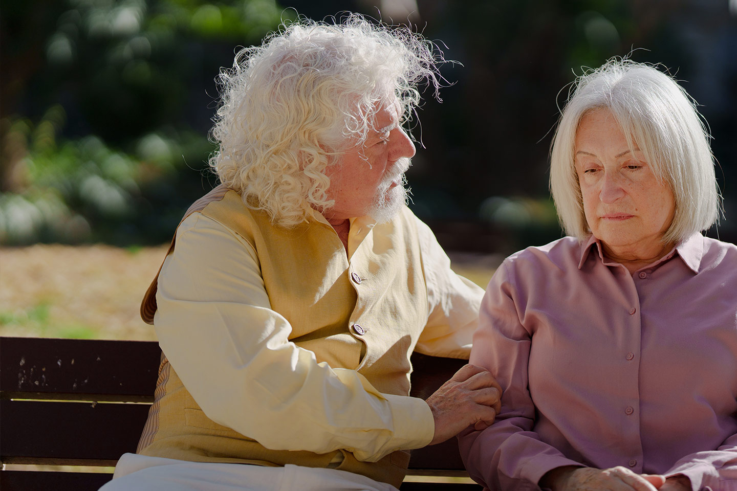 Photo of two people with white hair sitting on a park bench