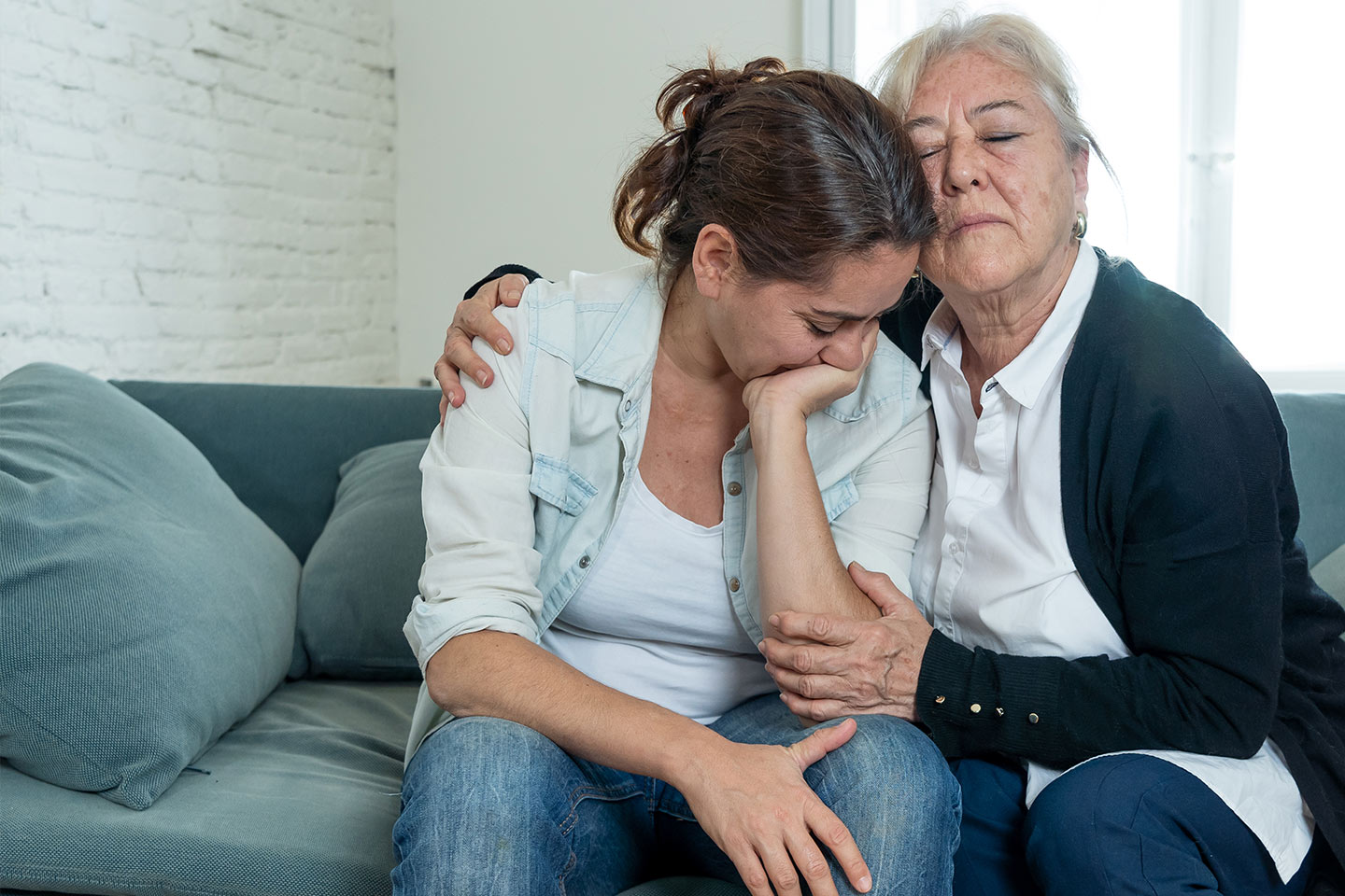 Photo of a woman comforting another woman on a sofa