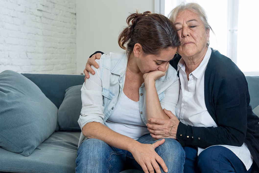Photo of a woman comforting another woman on a sofa