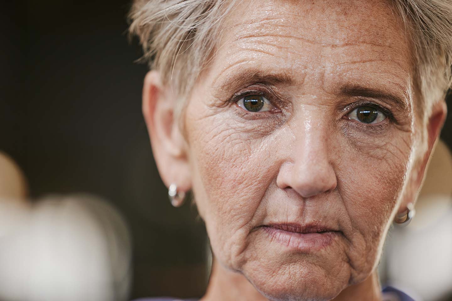 Photo of a woman with a grey pixie cut and shiny earrings
