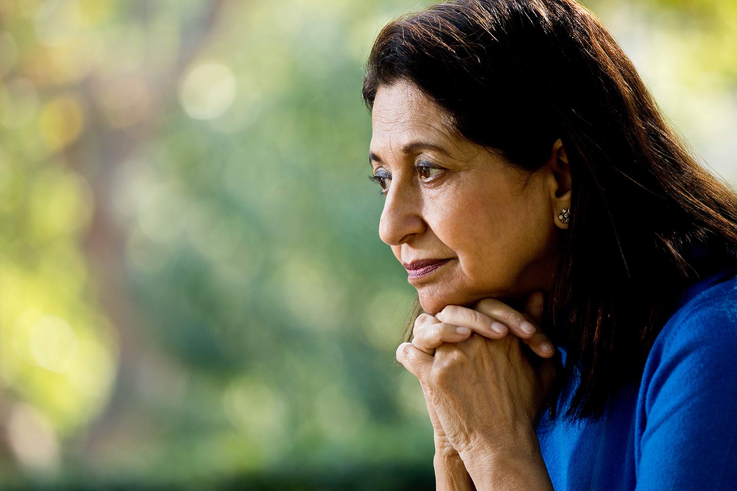 Photo of a woman in a royal blue shirt with chin on hands