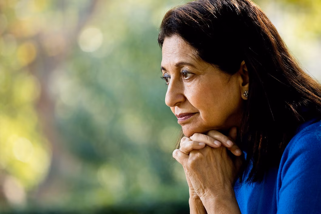 Photo of a woman in a royal blue shirt with chin on hands
