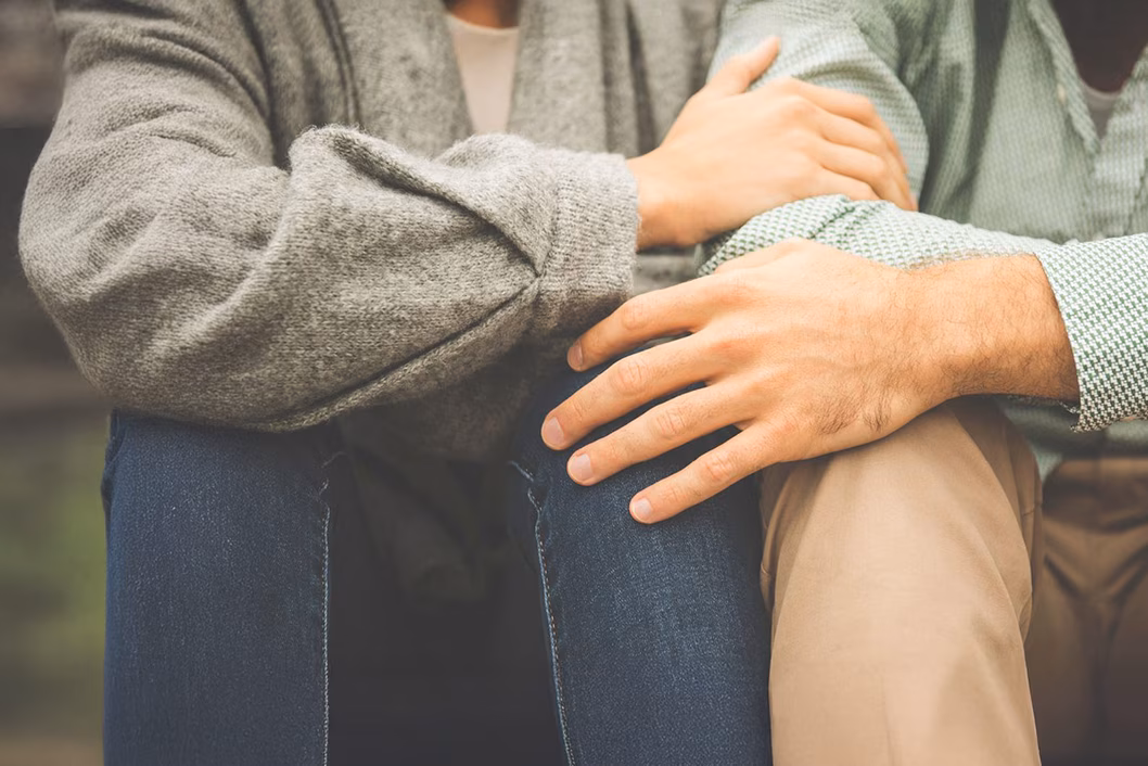Image of two people holding each other on the knee and arm