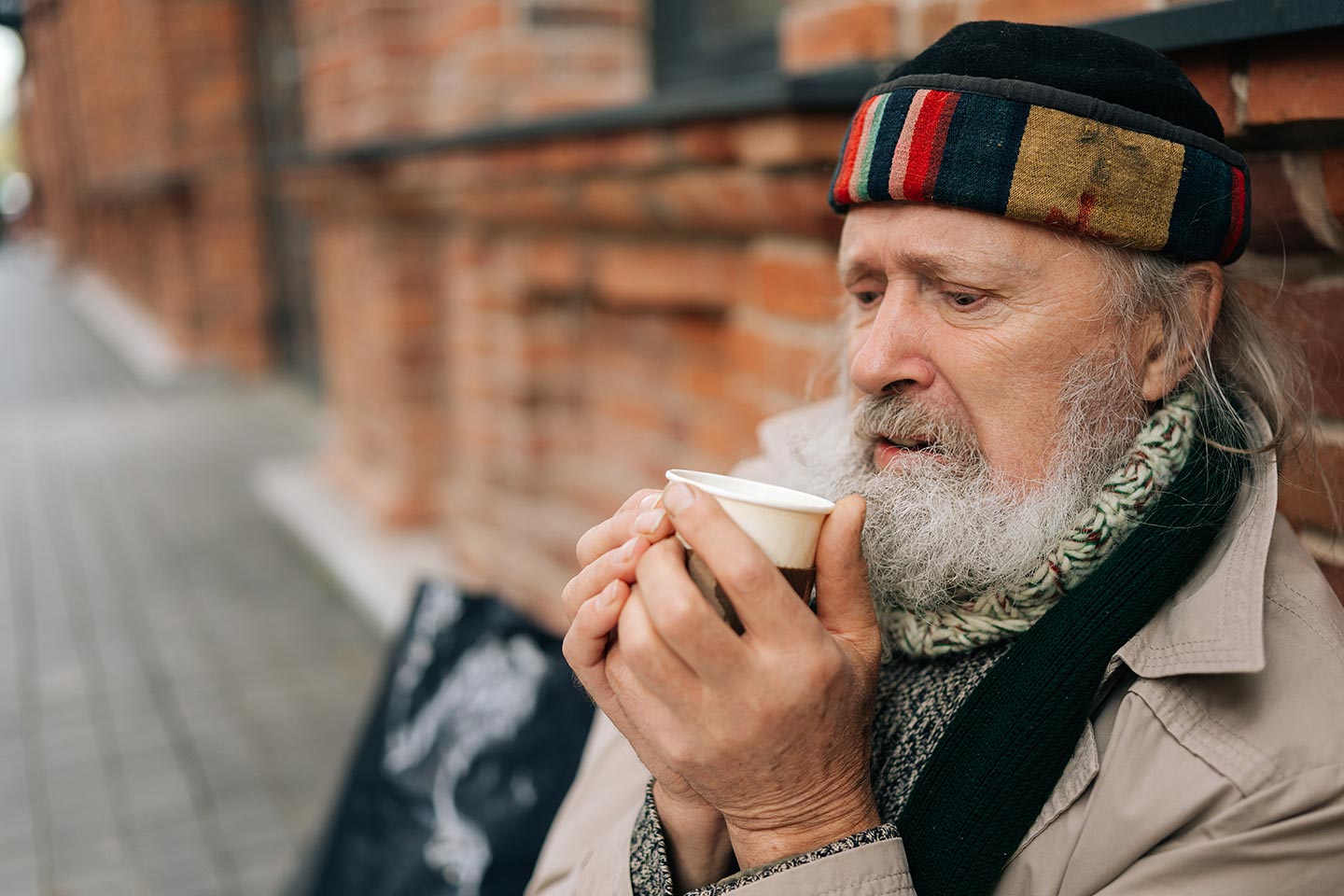 Photo of man in a colourful cap holding a takeaway coffee cup