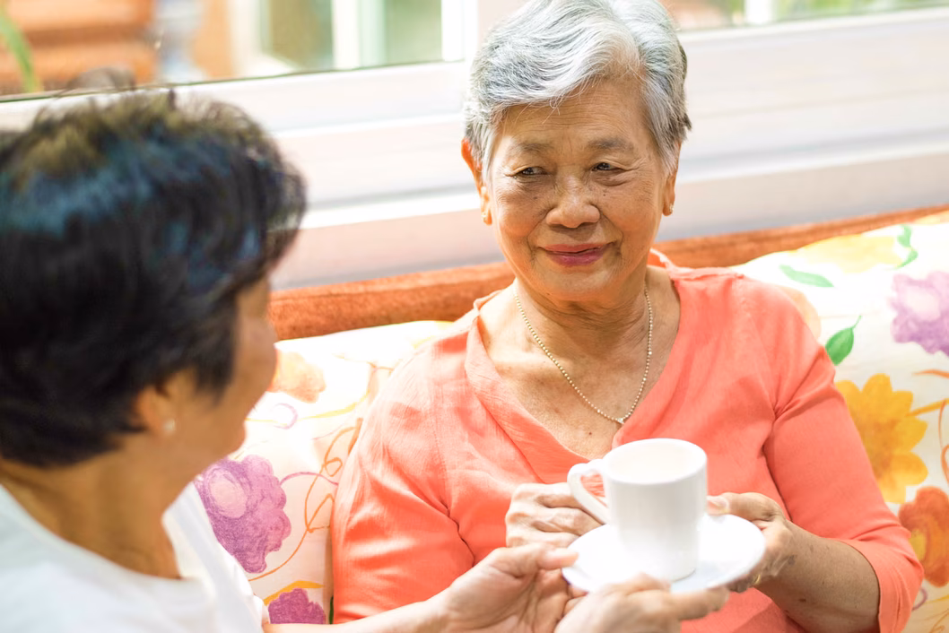 Senior woman drinking tea with adult daughter