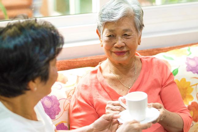 Senior woman drinking tea with adult daughter