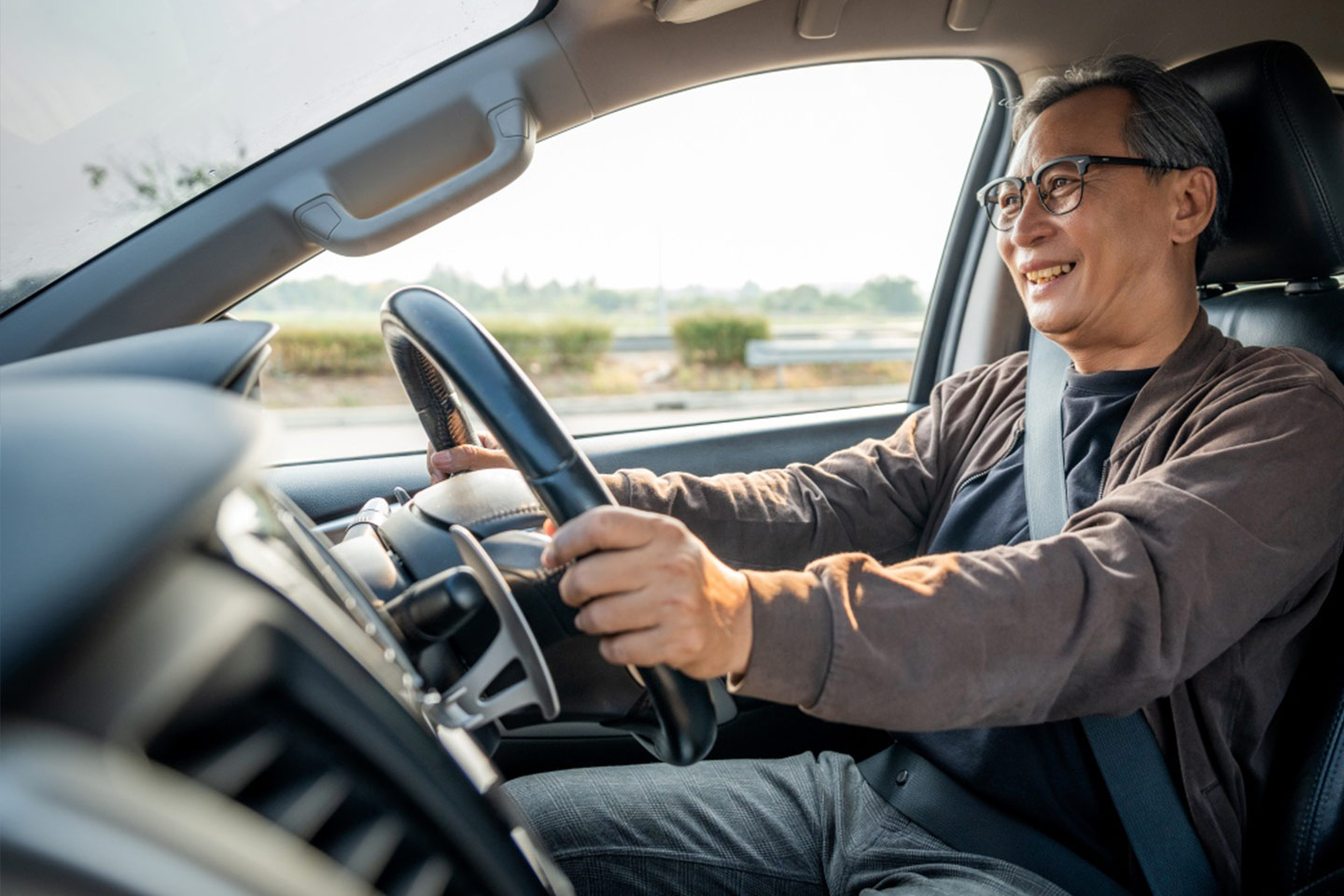 Photo of a smiling man behind the steering wheel of a car