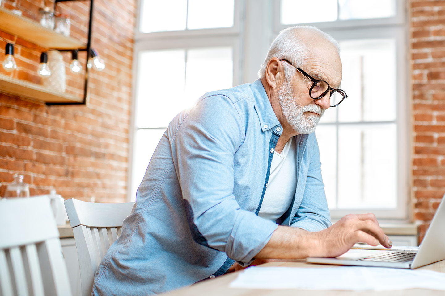 Photo of a man in a blue shirt using his laptop