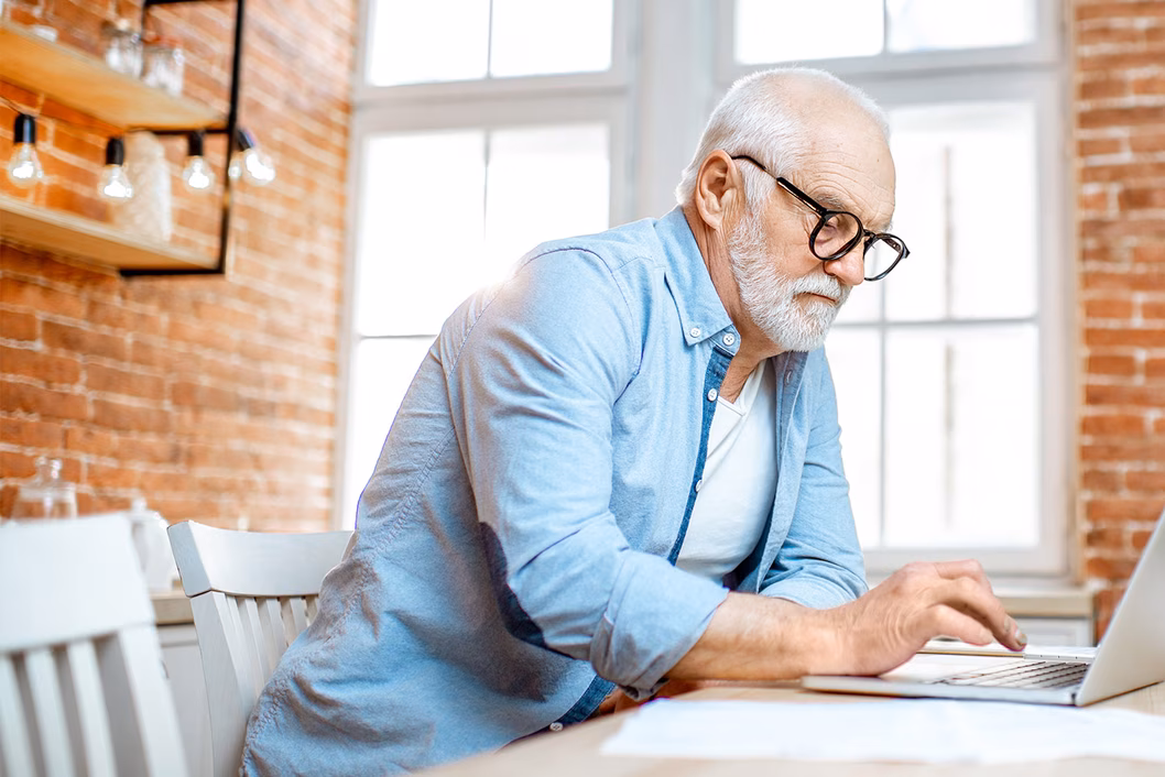 Photo of a man in a blue shirt using his laptop