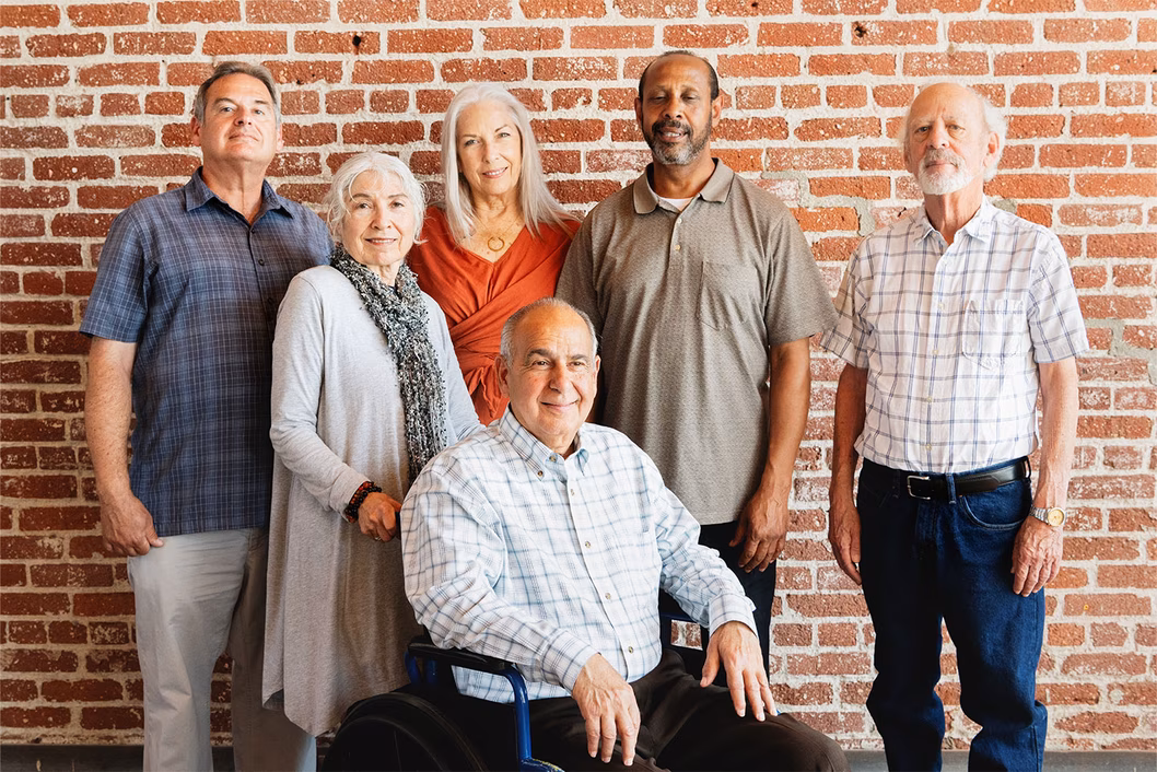 Image of a group of older people standing in front of a brick wall
