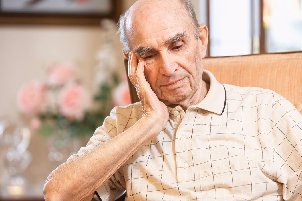 Photo of man in a tan chair resting his head on his hand