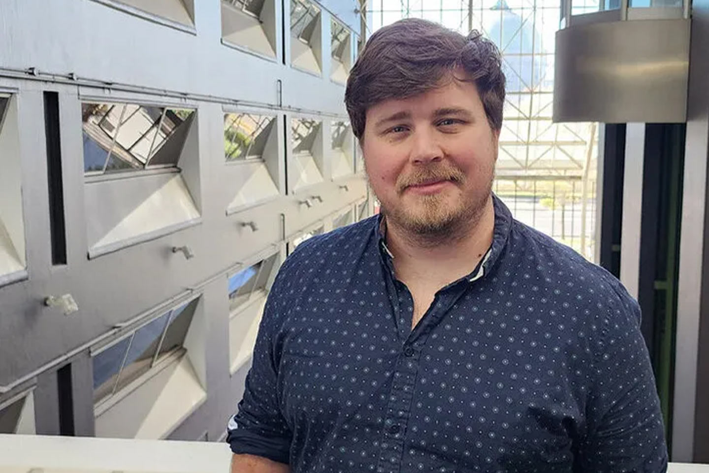 Photo of a bearded man wearing a blue shirt