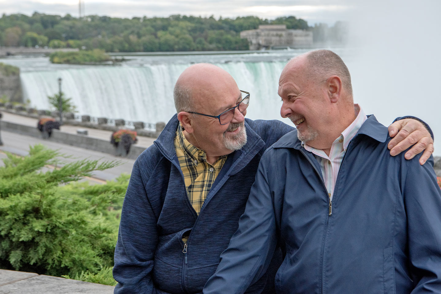Photo of two men embracing near a waterfall