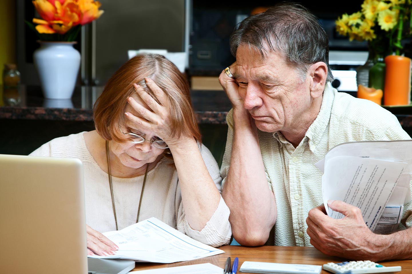 Image of an older woman and man reviewing documents in front of a laptop