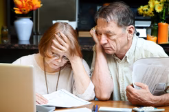 Image of an older woman and man reviewing documents in front of a laptop