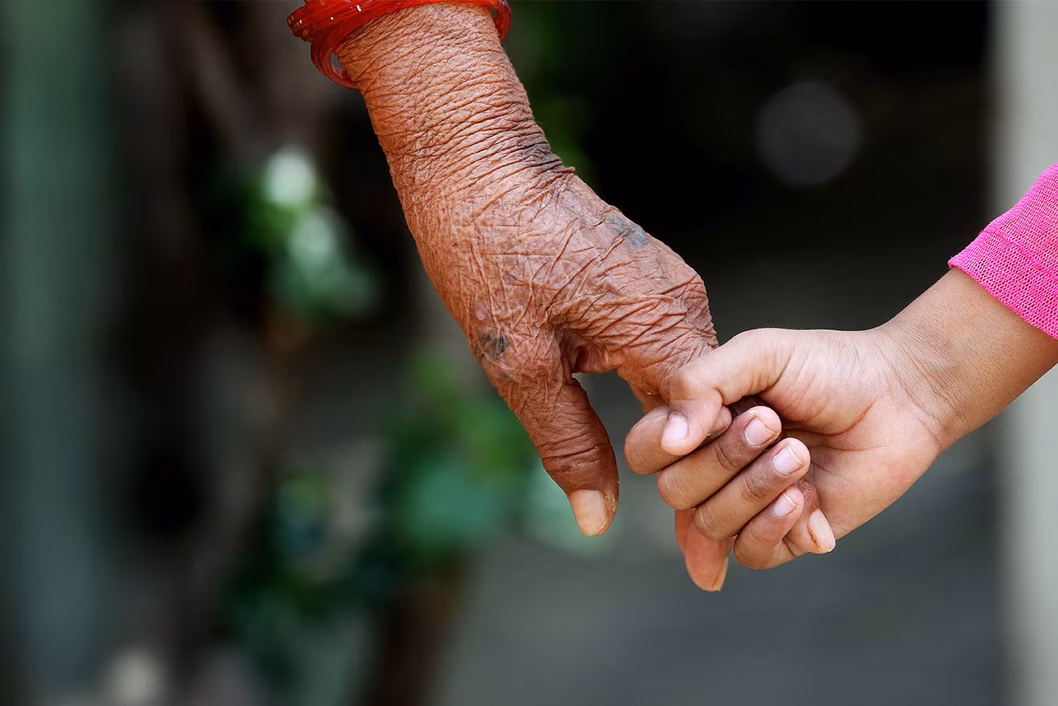 Photo of a younger hand holding an older hand